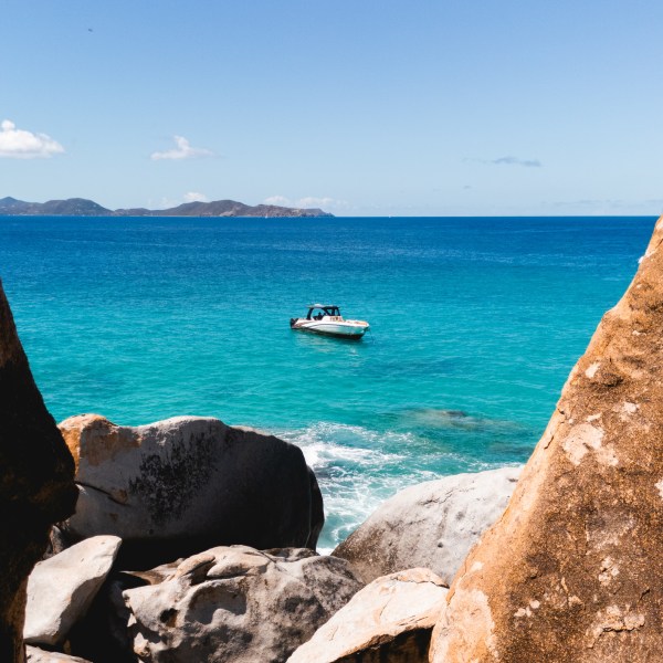 a group of people sitting on a rock near the ocean